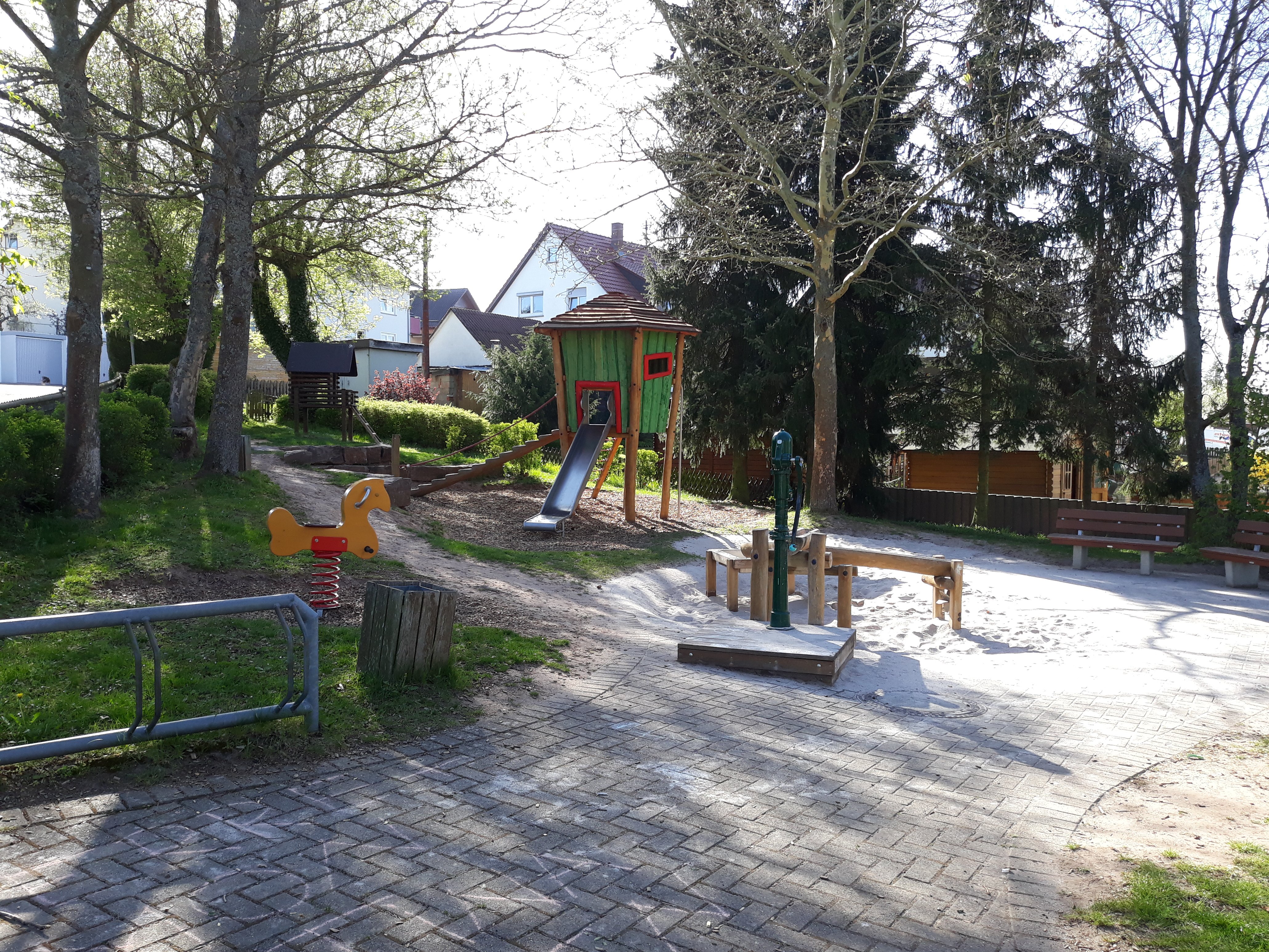Spielplatz Schulstraße mit Blick auf das Sandspielgerät, das Federwippgerät und den Spielturm mit Rutsche