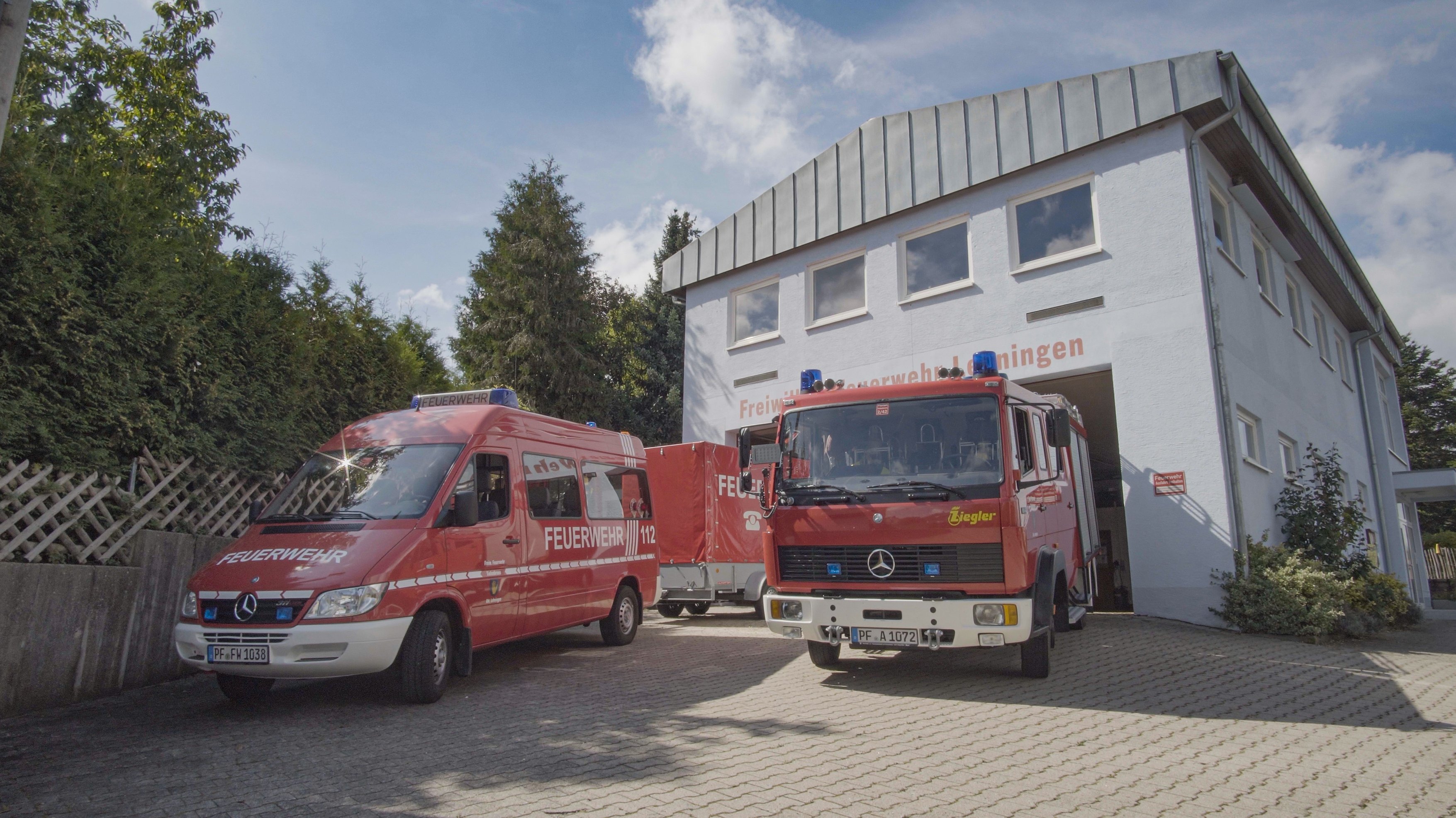 Vier unterschiedliche Feuerwehrfahrzeuge stehen vor dem Feuerwehrgerätehaus Lehningen