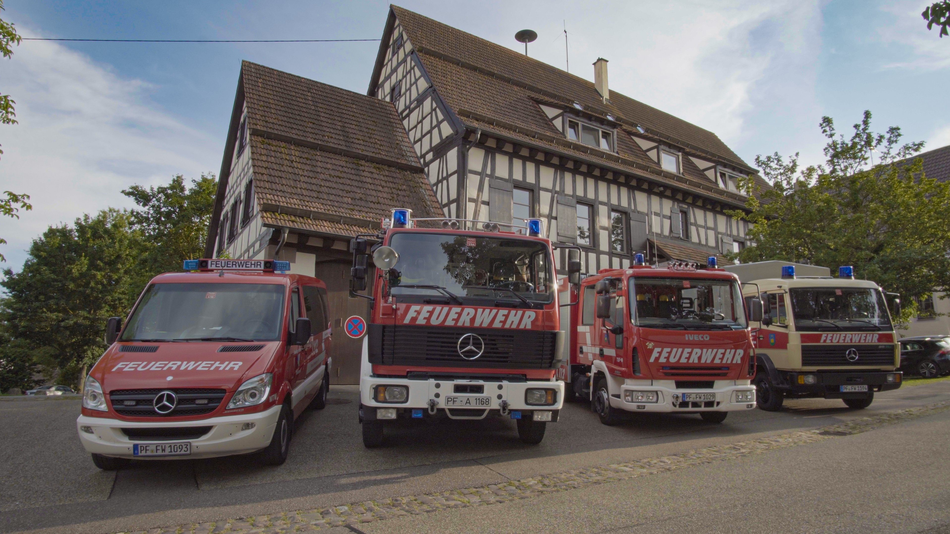 Vier unterschiedliche Feuerwehrfahrzeuge stehen vor dem Feuerwehrgerätehaus Tiefenbronn, auch Lammscheune genannt