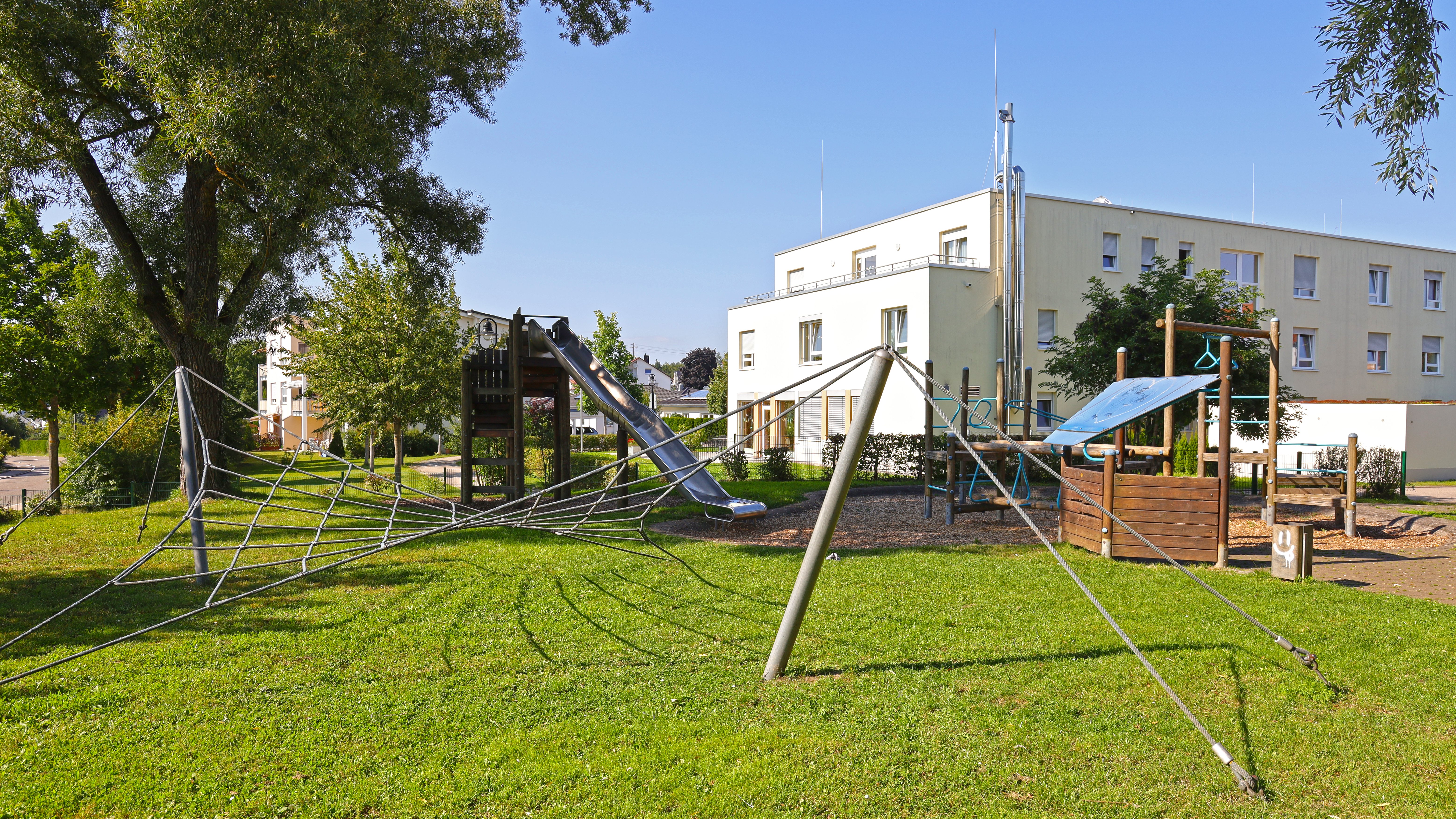 Foto vom Spielplatz Gemmingenhalle mit verschiedenen Spielgeräten wie eine Rutsche und Klettergerät sind zu sehen.